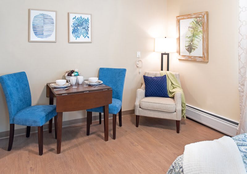 A cozy living and dining area with a small table, chairs, and artwork on the walls.