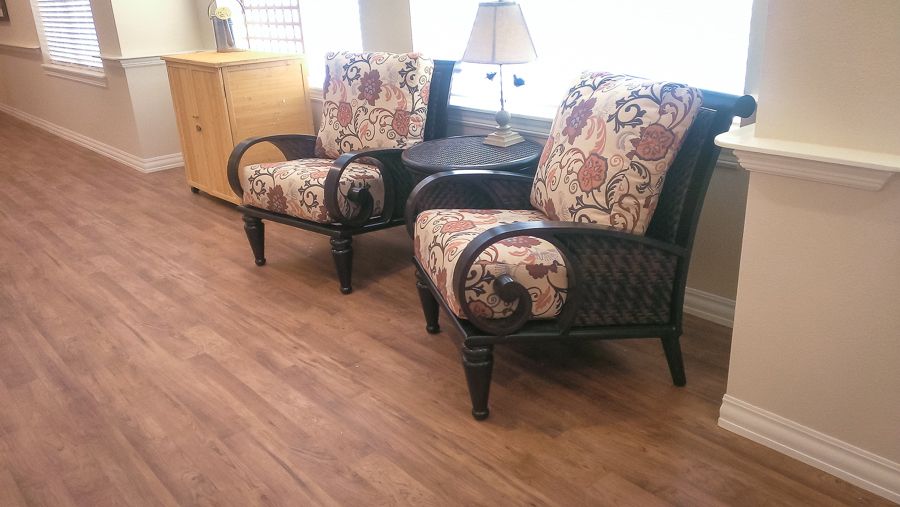 A cozy seating area featuring two upholstered chairs with a floral pattern next to a small round table and lamp on a wooden floor.