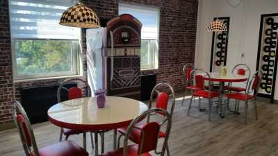 A retro diner with red chairs, a jukebox, and checkerboard-patterned lamp shades.