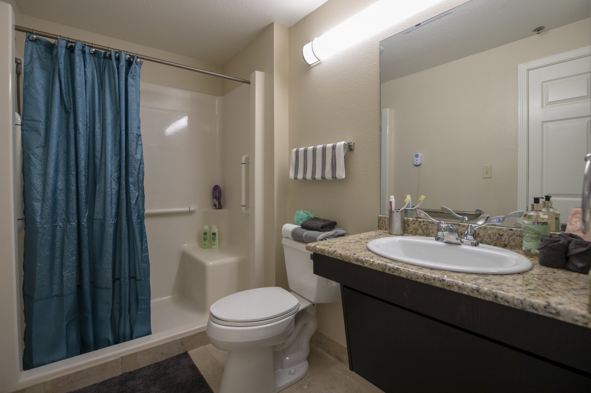 A clean and modern bathroom with a shower, toilet, sink, and mirror.