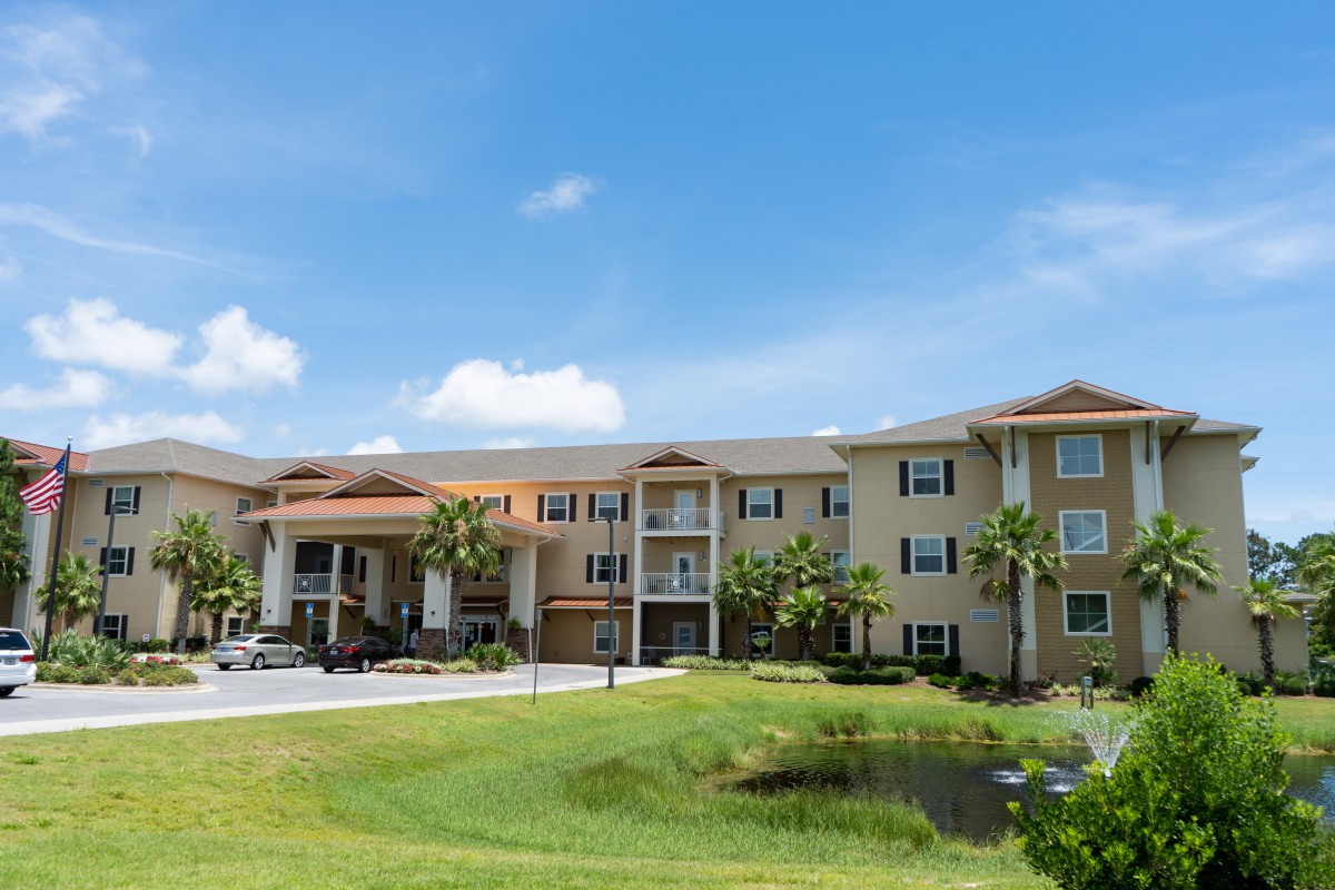 A view of a residential apartment complex with well-maintained landscaping under a clear blue sky.