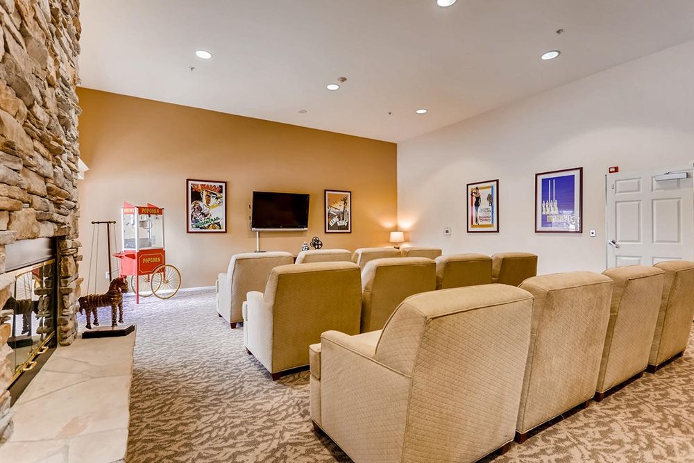 A cozy home theater setup with plush seating, a television, and decorative artwork.