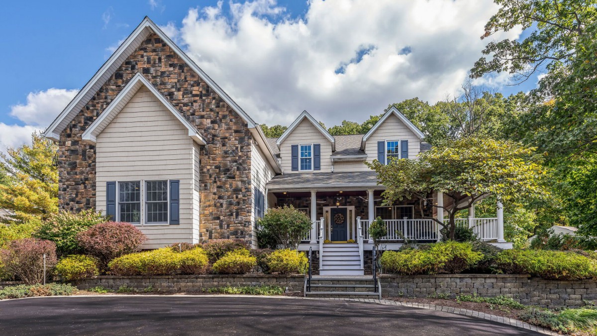 A beautiful residential house with a stone facade and a welcoming porch, surrounded by well-maintained landscaping.
