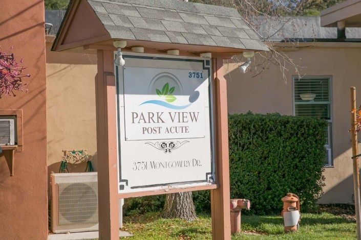 A sign for Park View Post Acute in front of a residential building.