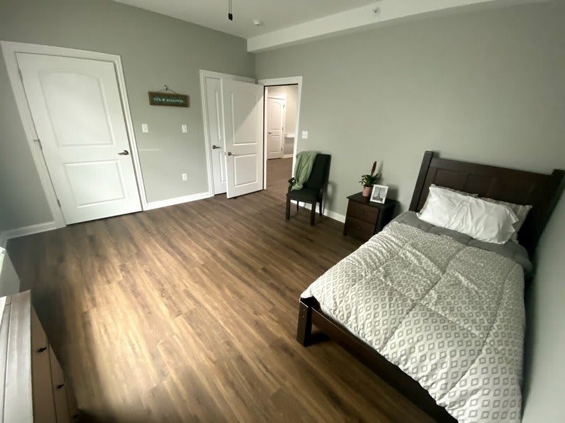 A minimalist bedroom with modern decor and wood flooring.