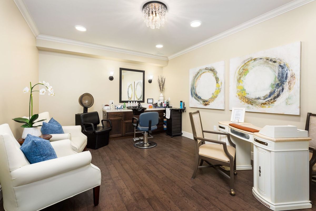 A modern office space with stylish decor, featuring a desk, chairs, and artwork on the walls.