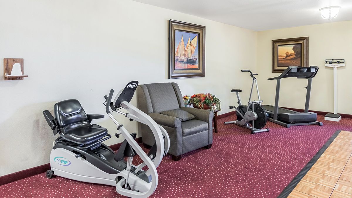 A small gym with exercise equipment including stationary bikes and a chair.