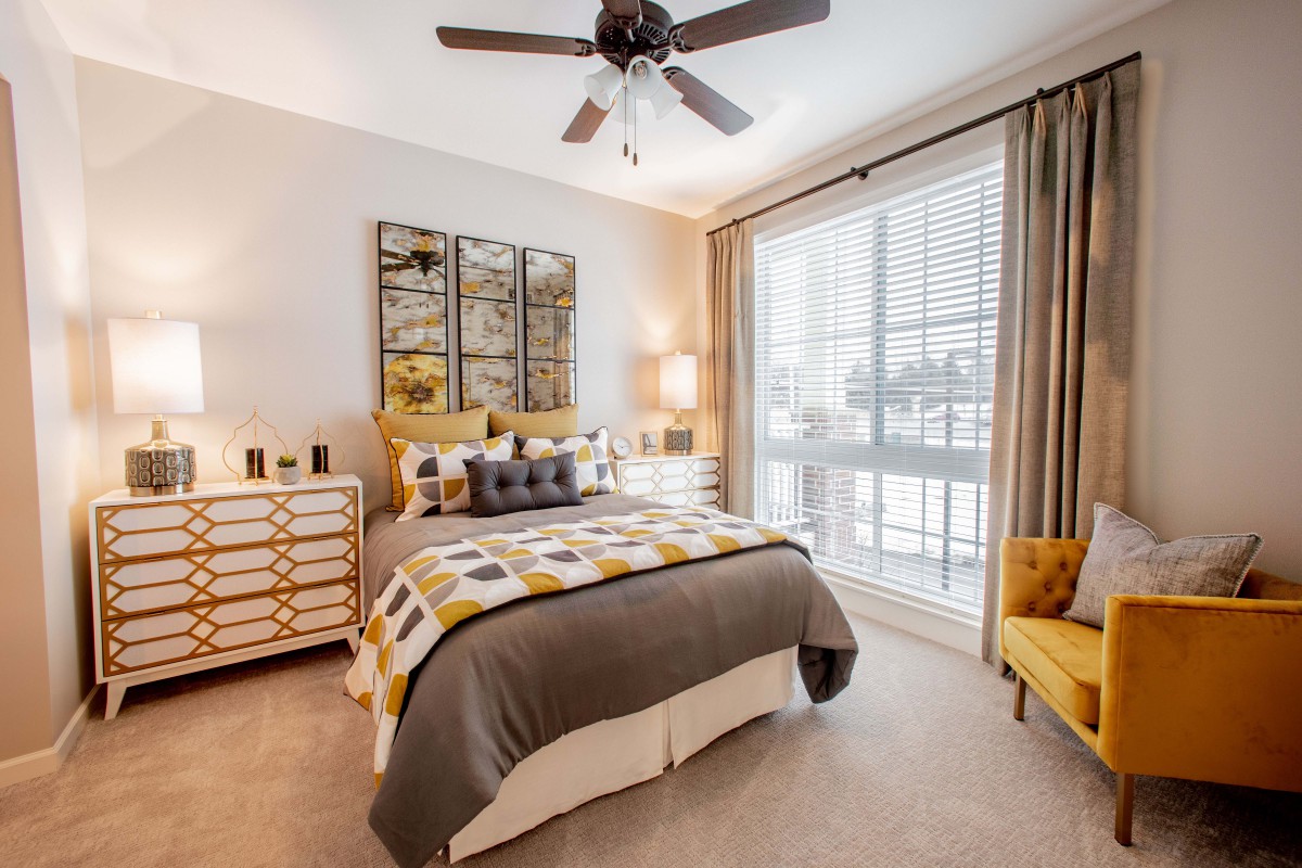A modern bedroom featuring stylish decor with a comfortable bed, decorative pillows, and ample natural light streaming through large windows.