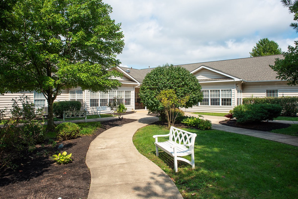 A peaceful garden with a bench and a winding pathway leading to a building.