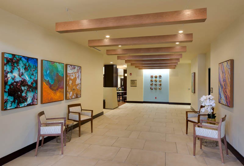 A modern lobby interior featuring colorful artwork, wooden beams, and seating.