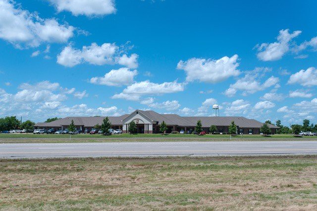 A wide view of a single-story building under a blue sky with scattered clouds.
