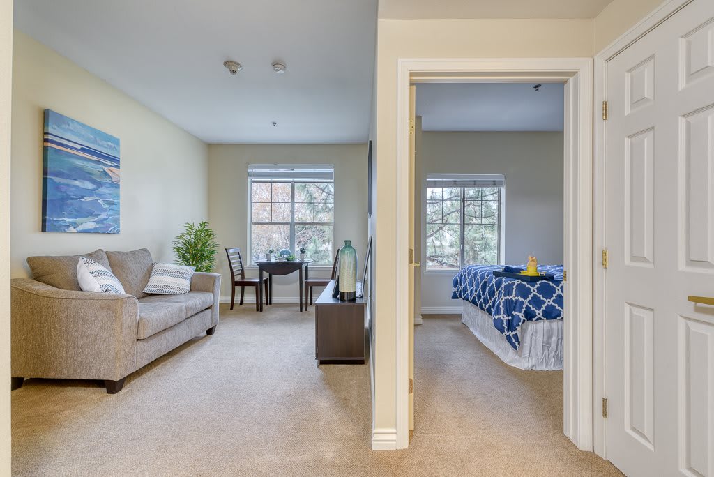 A cozy interior featuring a living room with a sofa and a table, adjacent to a bedroom with a neatly made bed.