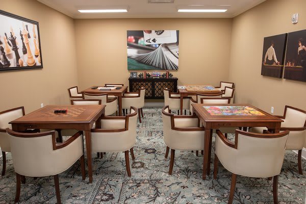 A well-lit room with tables and chairs arranged for a meeting or gathering, featuring artwork on the wall.