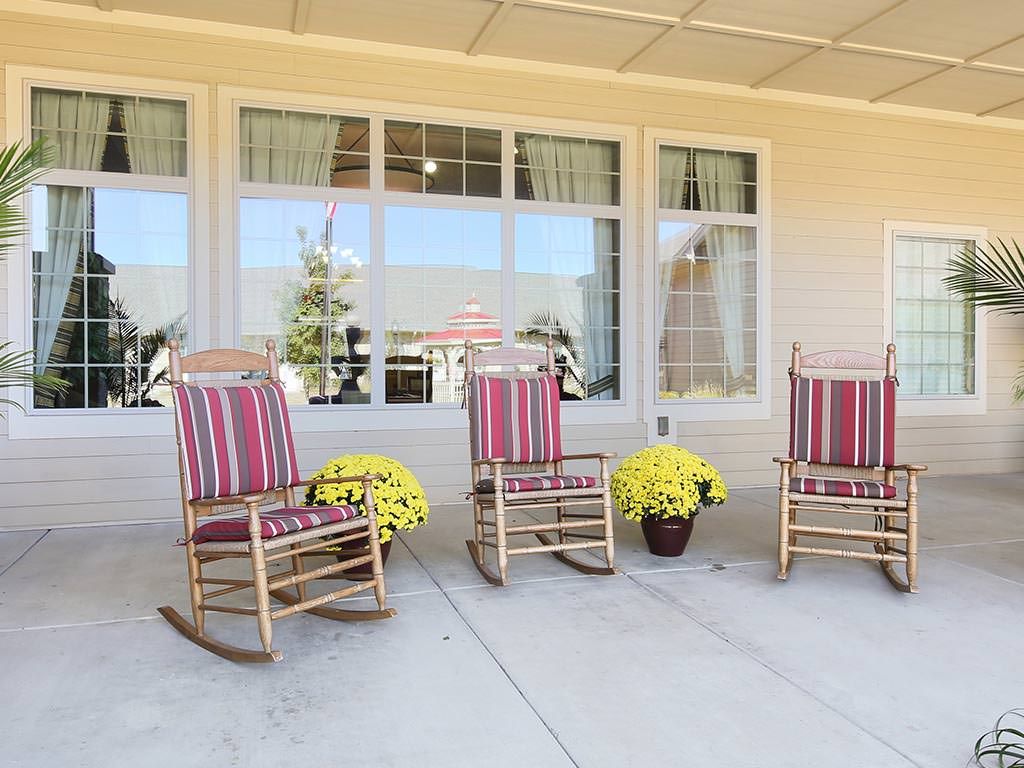 A cozy porch with striped rocking chairs and potted flowers.