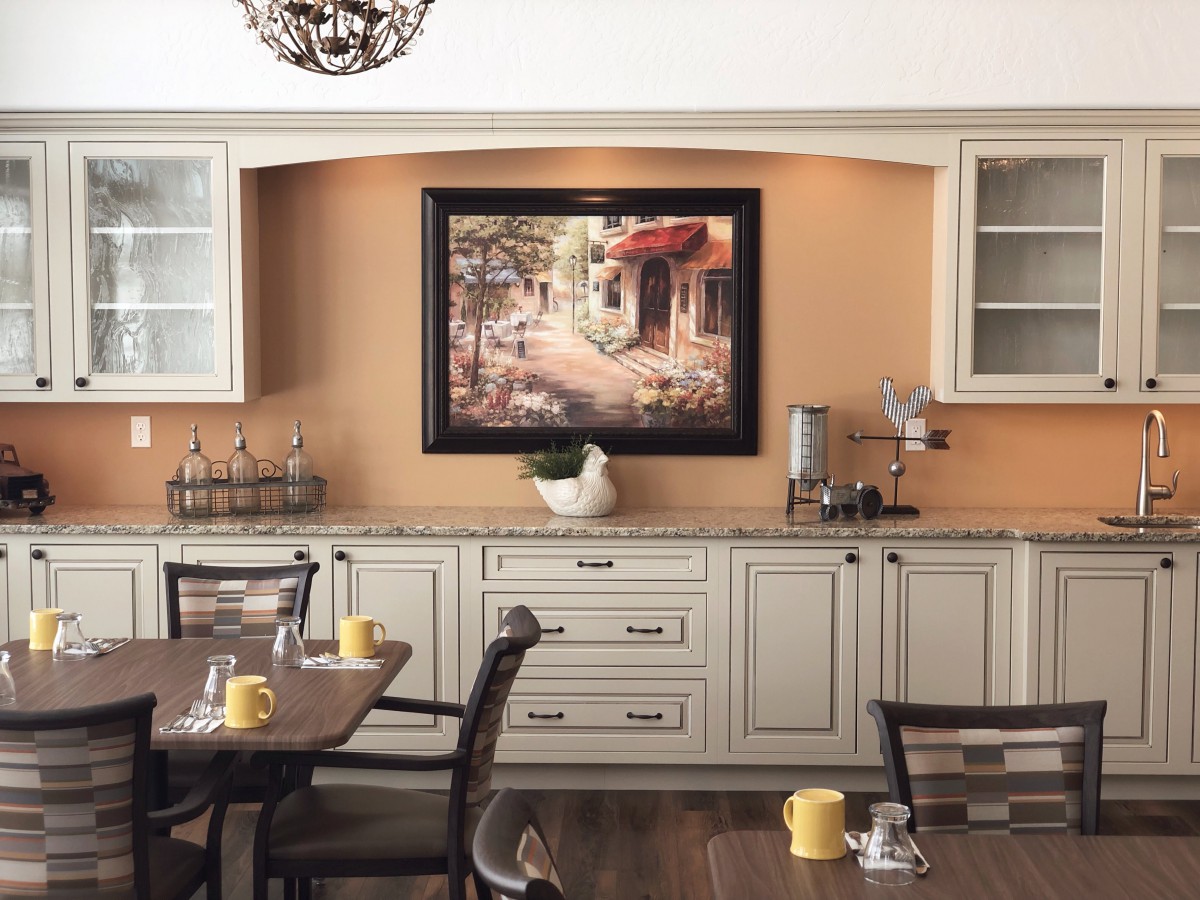 A cozy kitchen with elegant cabinets and a painting above the counter.