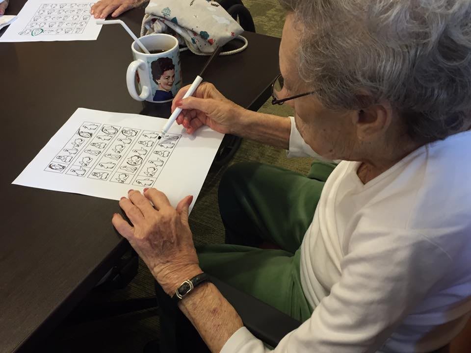 An elderly person engaged in solving a puzzle at a table.