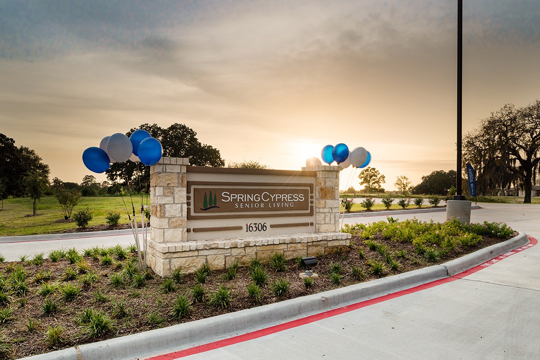 A scenic view of an entrance sign adorned with balloons at sunset.