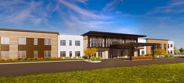 A modern building with a sleek design under a clear blue sky, surrounded by landscaped greenery.