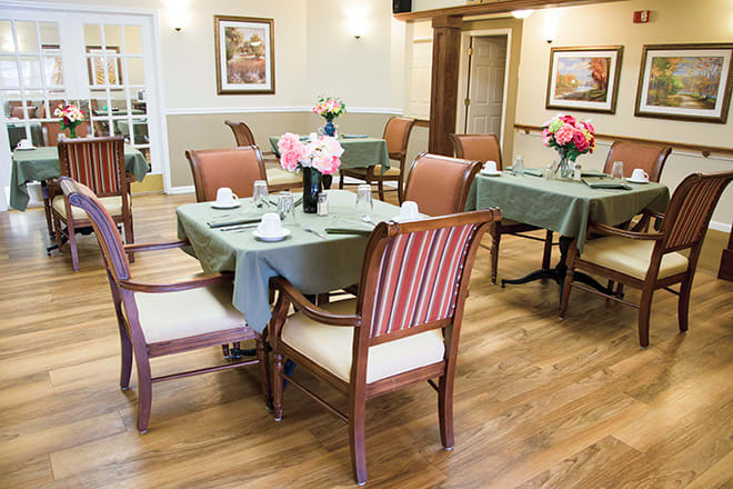 A well-arranged dining room with tables and chairs, featuring floral decorations and a cozy atmosphere.