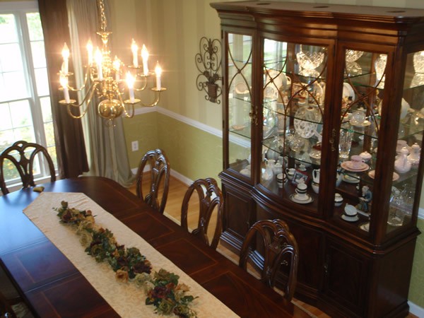 A beautifully decorated dining room featuring an elegant chandelier and a classic china cabinet.
