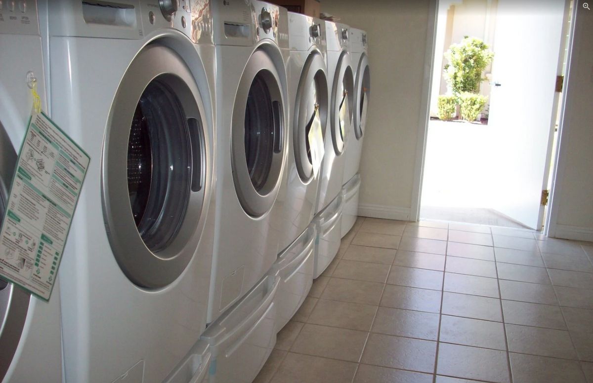 A row of washing machines lined up in a laundromat.