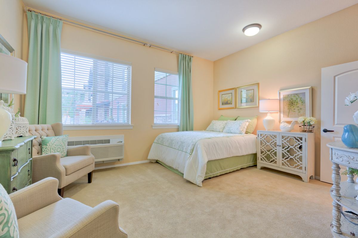 A cozy and well-lit bedroom with a bed, armchair, and stylish decor.