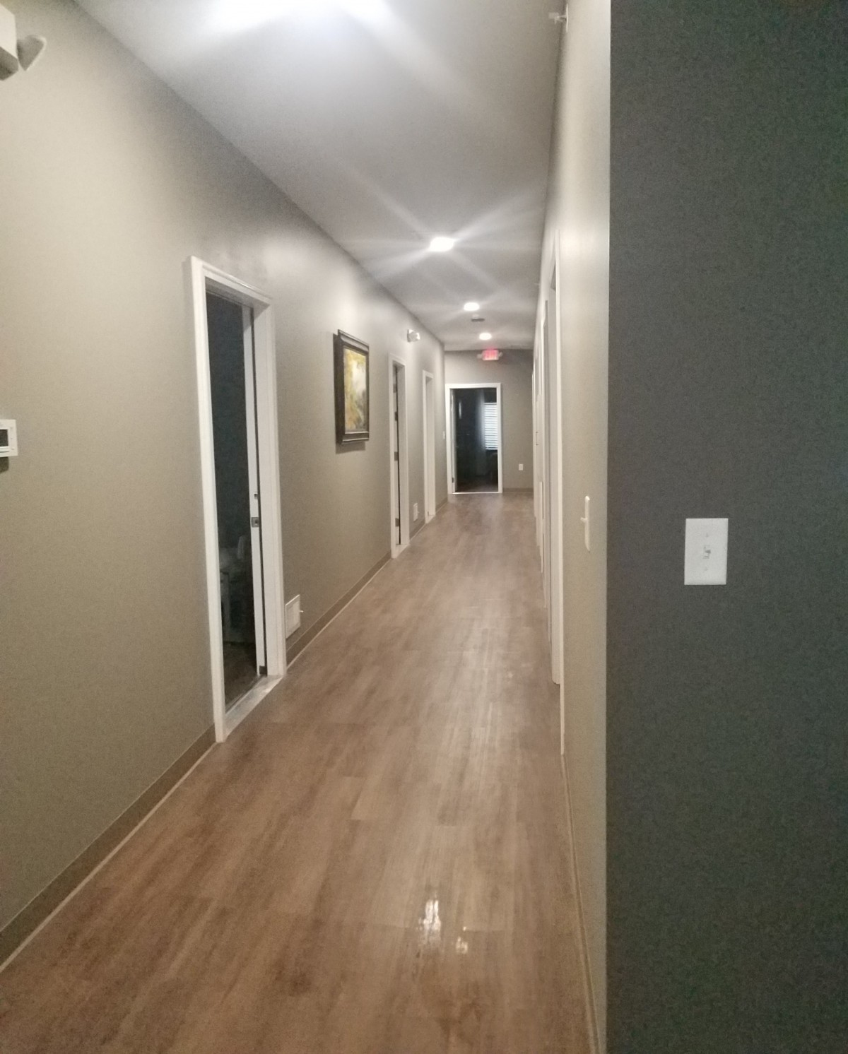 A long indoor hallway with several doors and modern lighting.