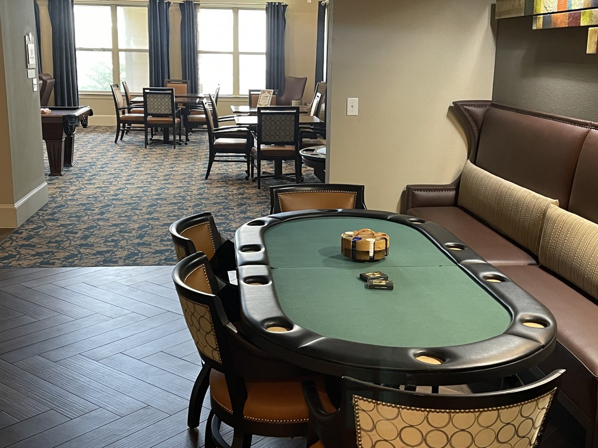A well-furnished interior featuring a poker table and chairs, ideal for card games.