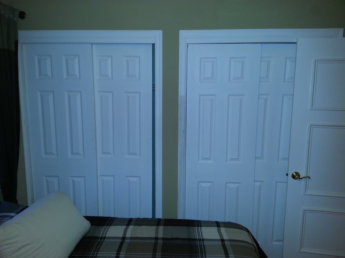 A bedroom featuring a bed with a plaid blanket and two white doors.