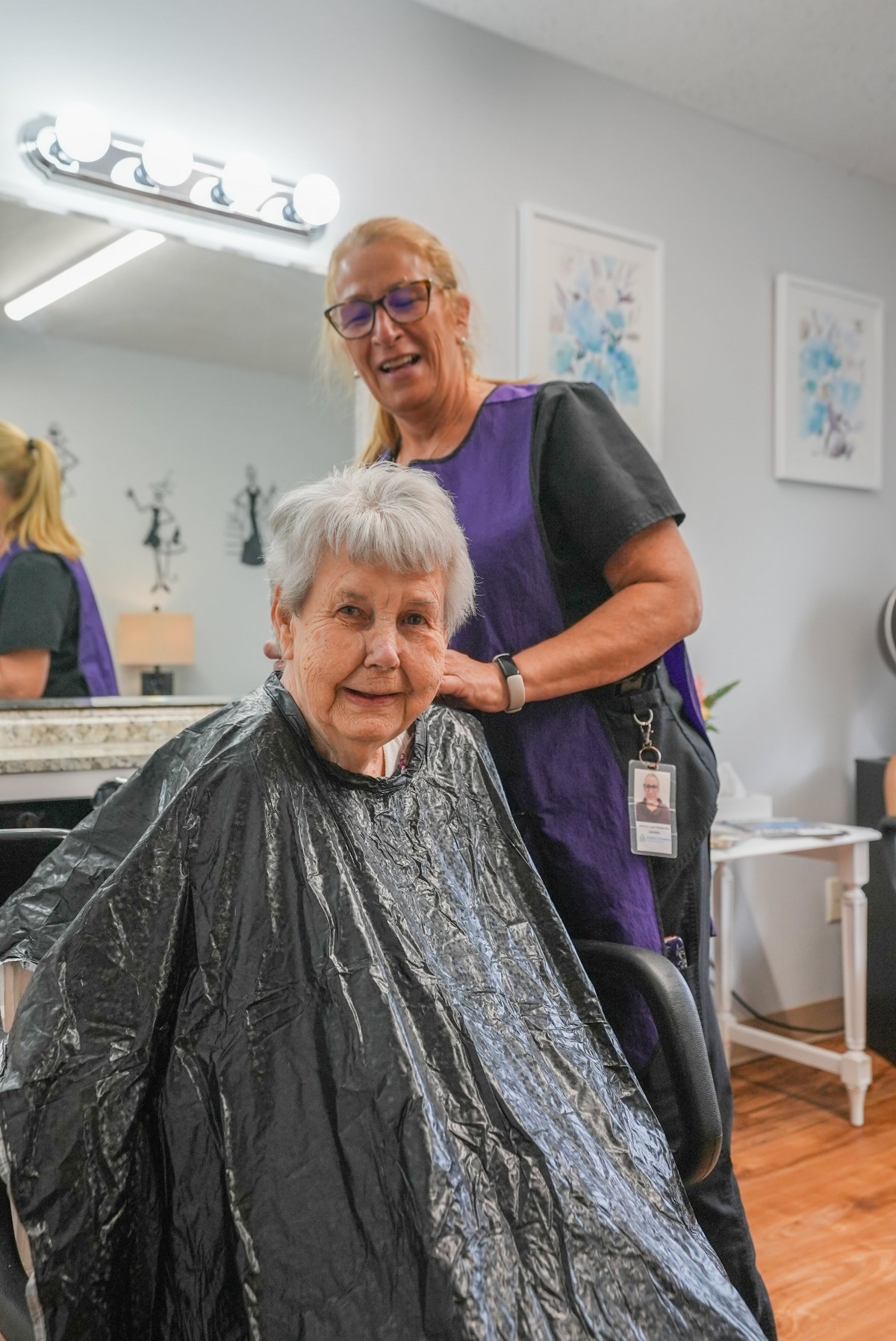 An elderly woman getting a haircut from a hairstylist at a salon.