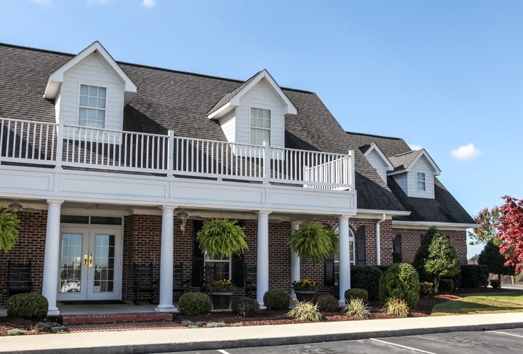 A large house with a front porch and balcony under a clear blue sky.