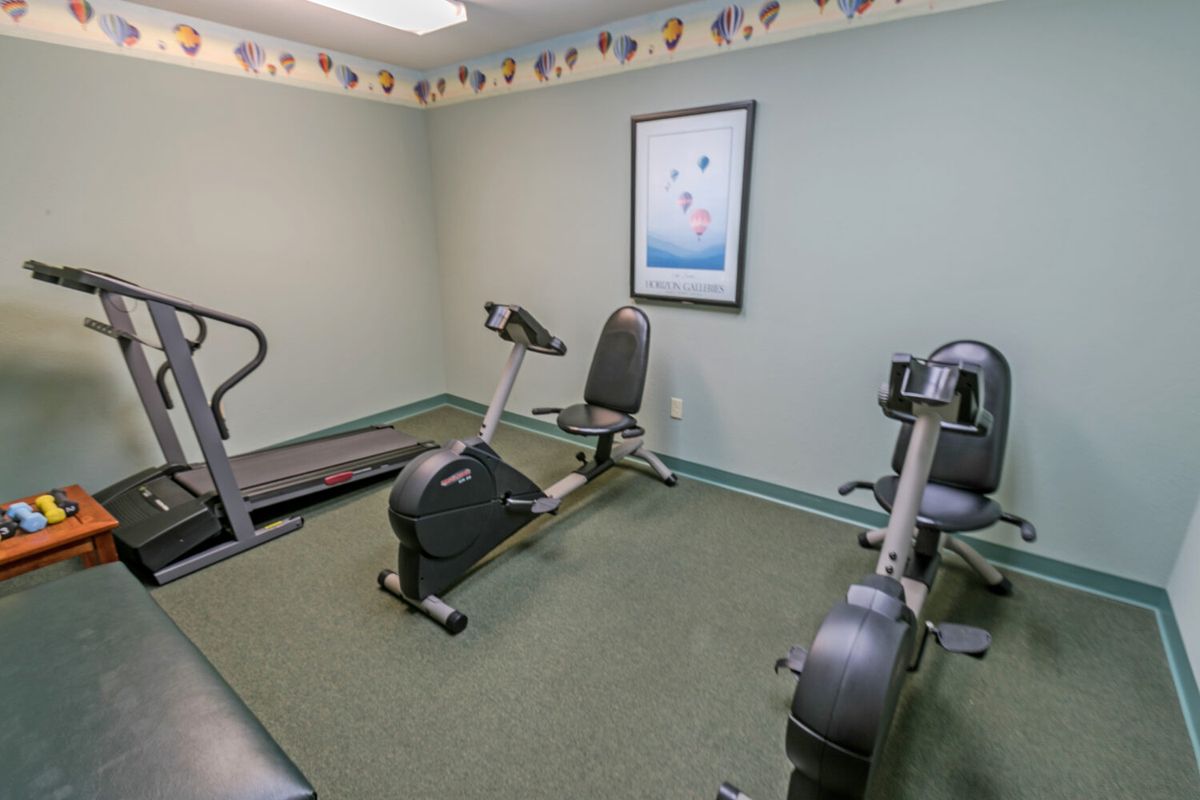 A small fitness room equipped with a treadmill and stationary bikes.