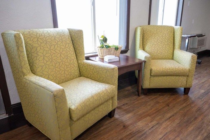 A pair of yellow armchairs next to a small wooden table in a bright living room.