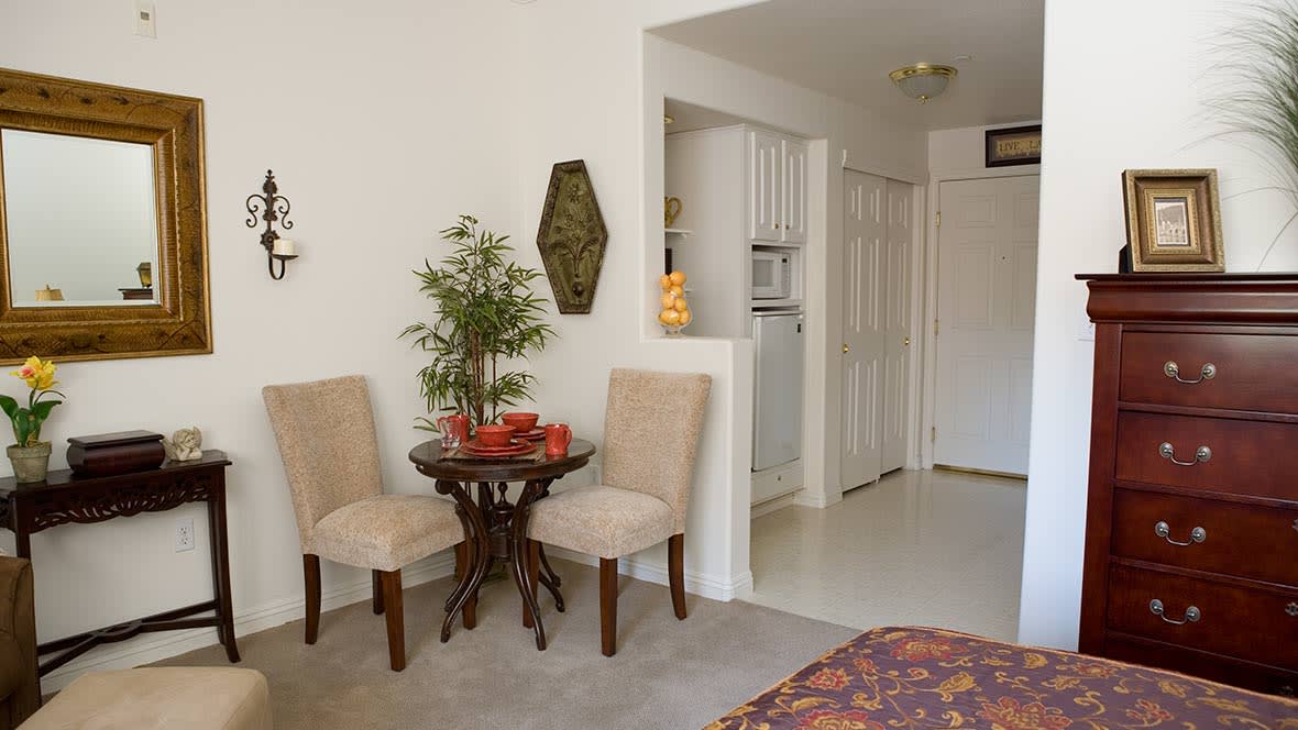 A cozy living room corner with a small dining table and two chairs, adorned with decorative elements and a potted plant.