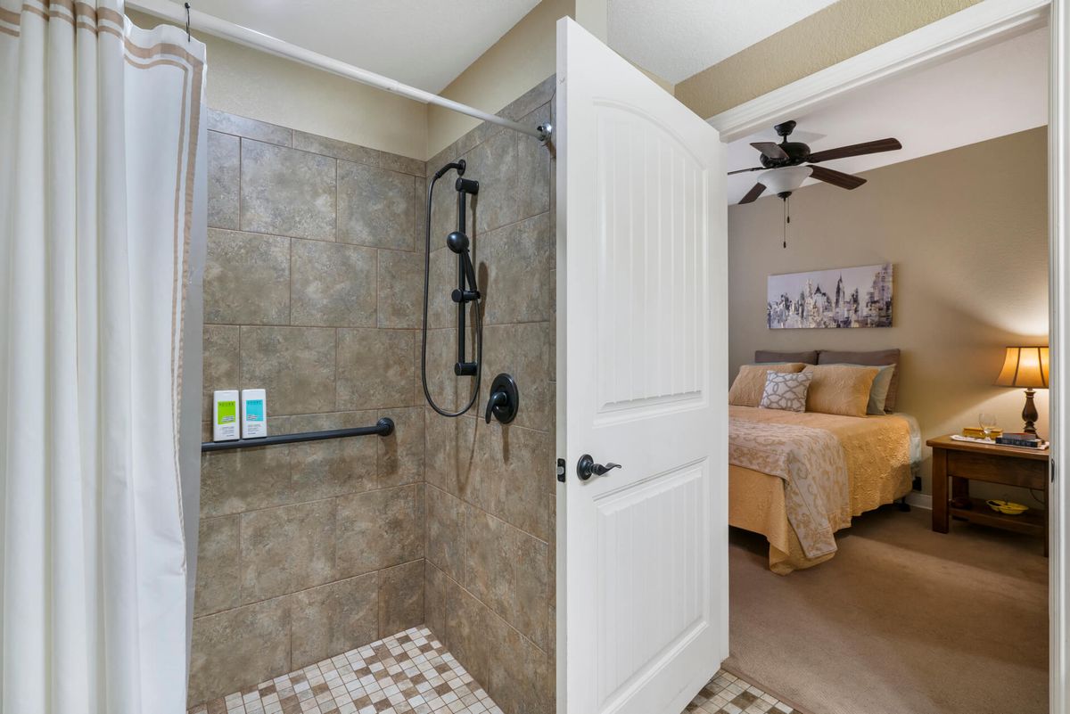 A cozy bedroom adjacent to a modern tiled shower area.