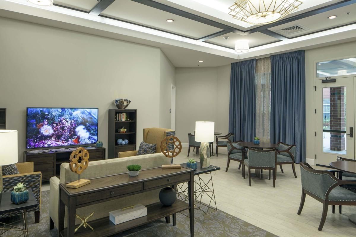 A modern living room with elegant furniture and decor, featuring a TV and dining area.