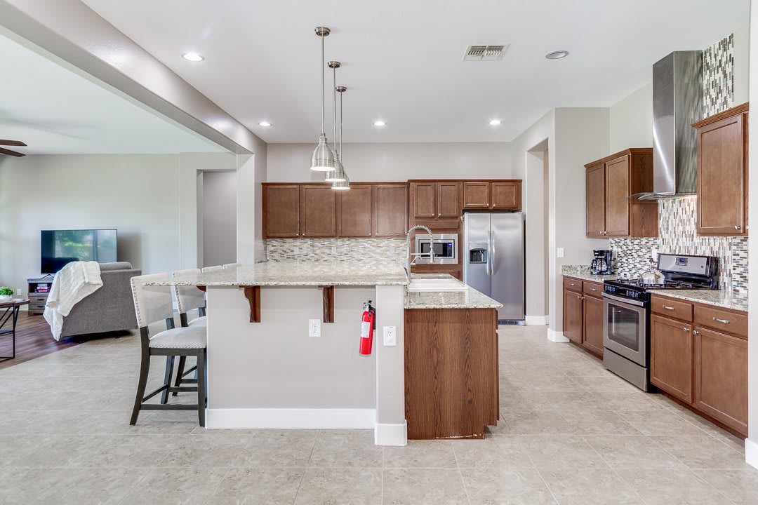 A modern kitchen with wooden cabinets, stainless steel appliances, and a central island with bar stools.