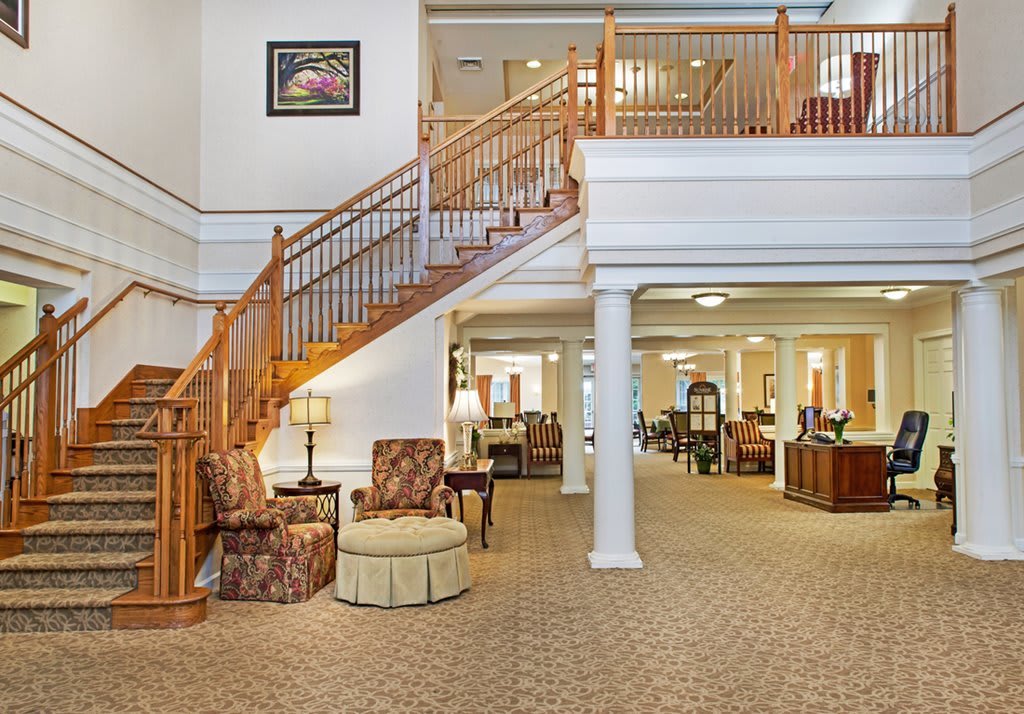 A spacious and elegantly designed lobby with a staircase, seating area, and decor.