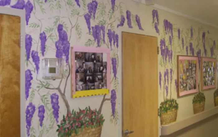 A hallway with a vibrant wall mural featuring purple flowers, a wooden door, and a photo collage.