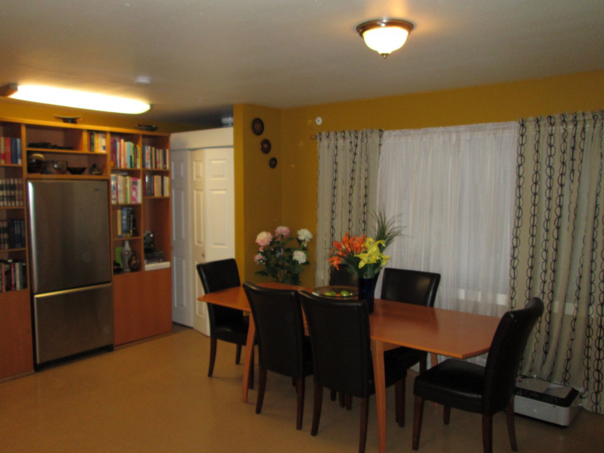 A cozy dining room with a wooden table and black chairs, adorned with floral arrangements.