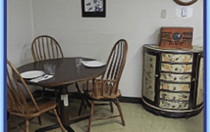 A cozy dining area with a wooden table set and chairs, prepared with plates and cutlery.