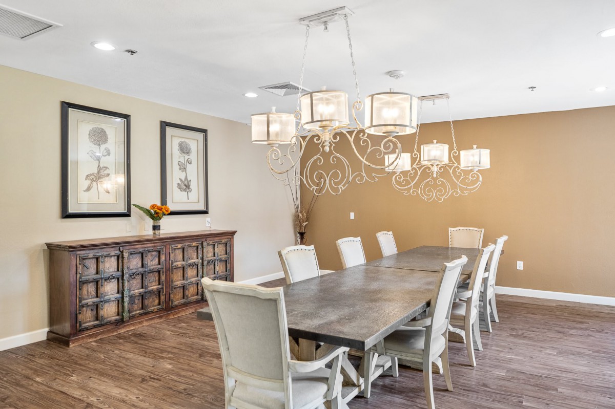 A sophisticated dining room featuring a long table with elegant chairs, a decorative chandelier, and tasteful wall art.