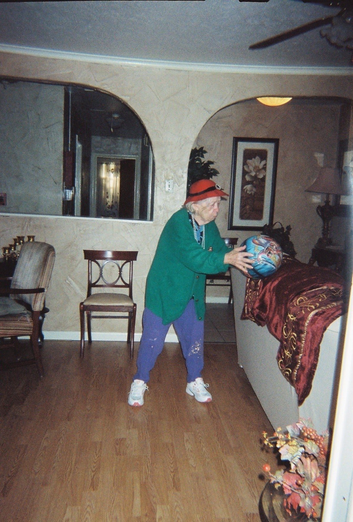A person in casual clothing is playing with a ball indoors, in a living room setting.