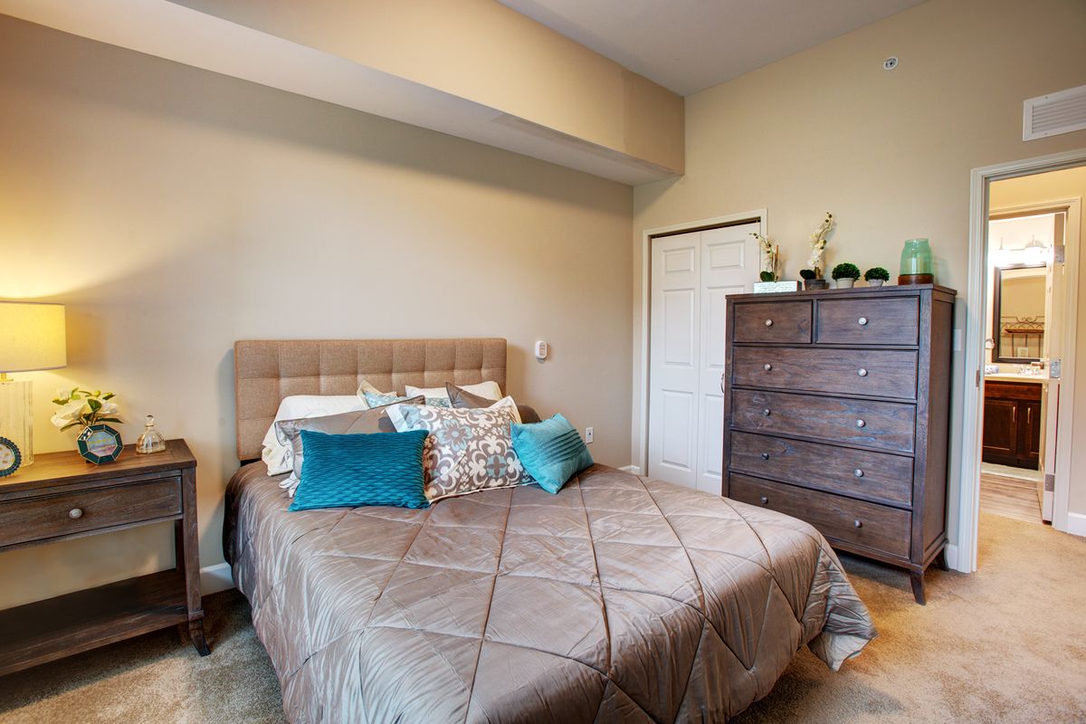 A cozy bedroom with a neatly made bed and a dresser.