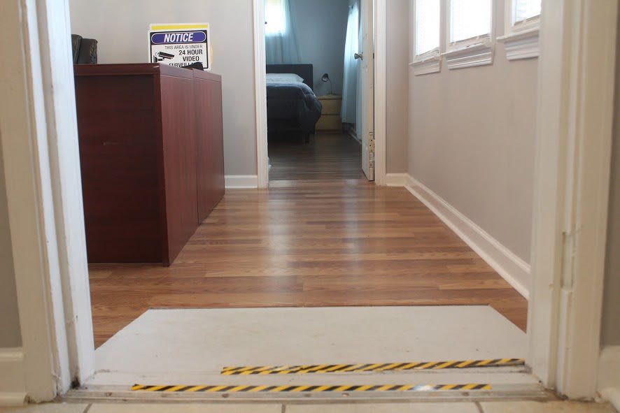 The image shows a hallway with hardwood flooring leading to a bedroom and office space.