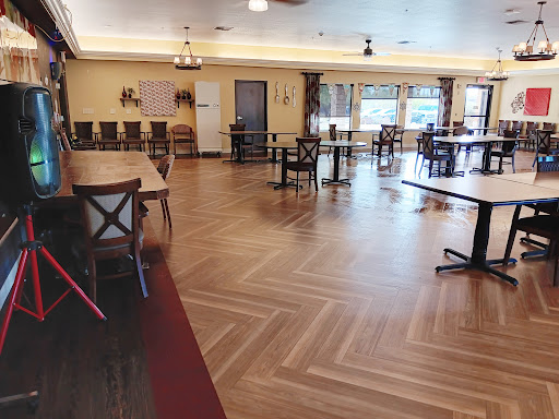 A spacious and well-lit dining area with wooden floors and neatly arranged tables and chairs.