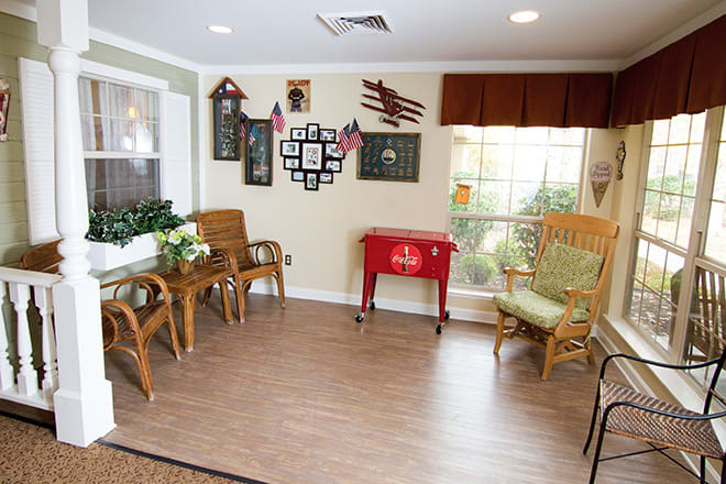 A cozy living room with wicker furniture, wall decorations, and a red cooler.