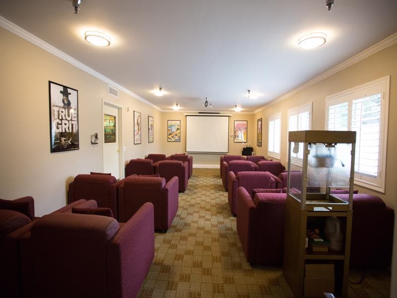 A cozy home theater room featuring comfortable armchairs and a projector screen, adorned with movie posters on the walls.