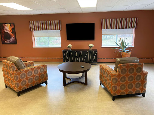 A cozy living room setup with patterned chairs, a coffee table, and a television on the wall.