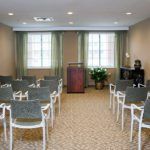 An empty conference room with rows of chairs facing a podium.